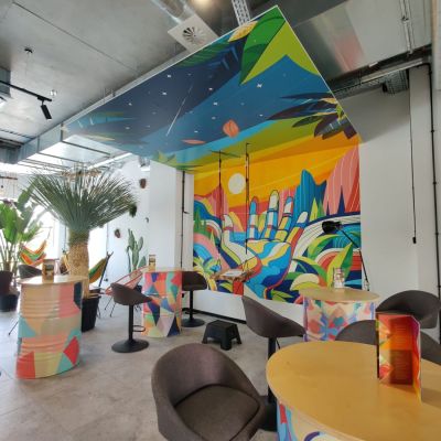 mural w kawiarni na ścianie, drukowany również na suficie, pełnokolorowa grafika przedstawiająca rękę na tle kolorowego świata, druk ścienny oddał głębię kolorów